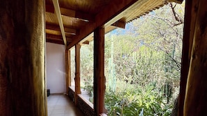 A corridor with wooden beams and large windows overlooking a garden with various plants. - hostal qachisolcor (San Pedro de Atacama)