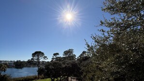 Una terraza con barandilla que da a un lago, árboles y un área con césped.