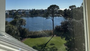 Vista de un lago con una casa al fondo y un árbol en primer plano.