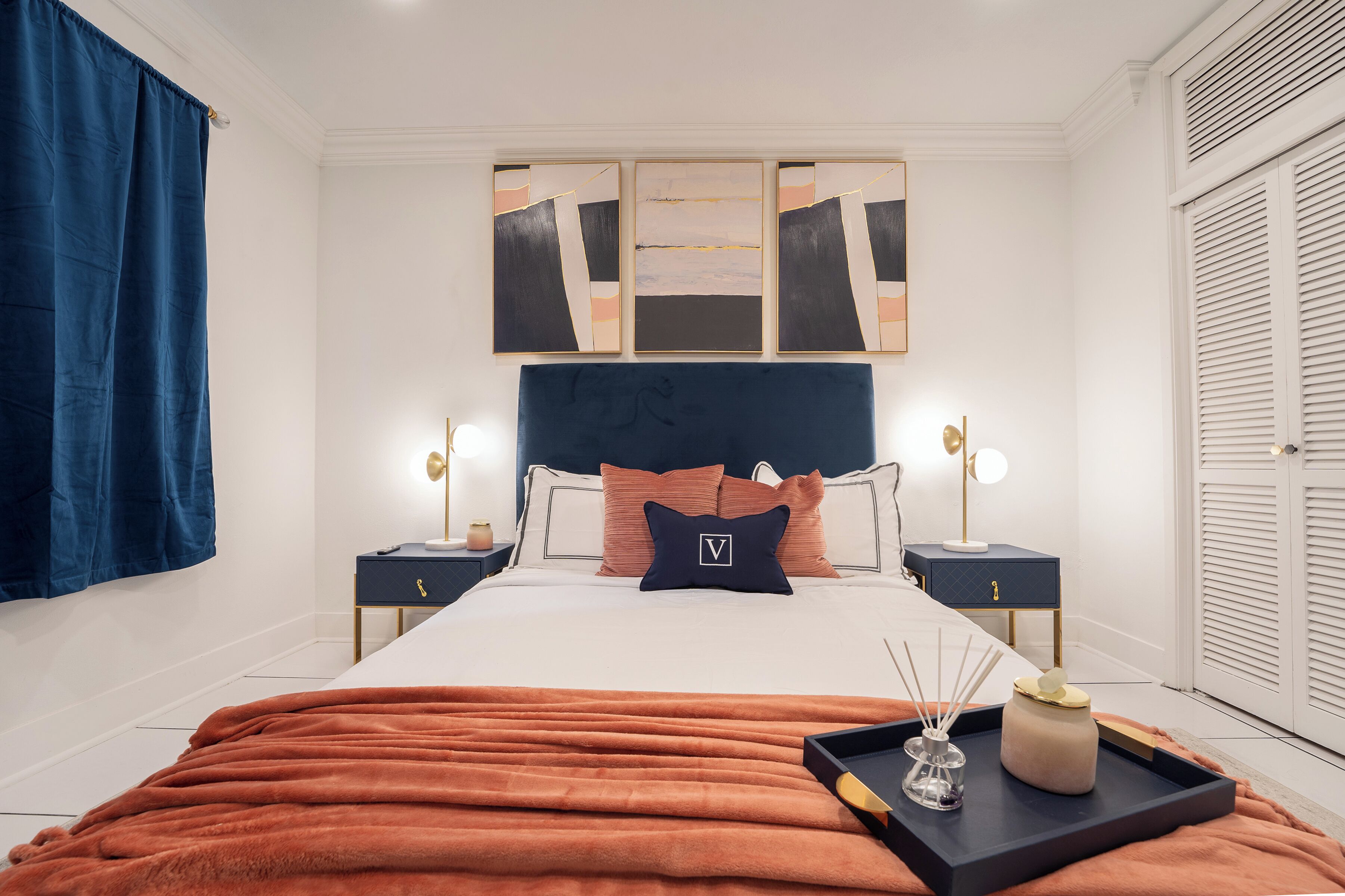 A neatly arranged bedroom with a large bed, two bedside tables, a wall-mounted artwork, and a wardrobe.