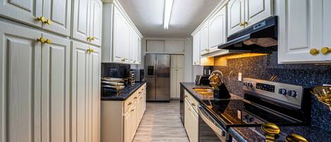 A modern kitchen with white cabinetry, stainless steel appliances, and granite countertops.