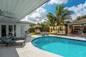 Une piscine avec des chaises longues, un patio couvert et une clôture en bois.