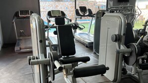 Un gimnasio con cintas de correr, máquinas de pesas y un ventilador.