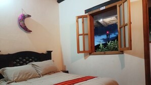 Un dormitorio con cama, ventana que ofrece vistas de la noche y una luna creciente decorativa en la pared.