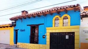 Un edificio con fachada azul, puerta amarilla y portón negro.