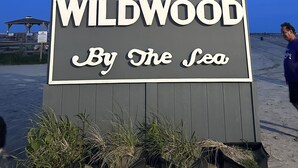 A sign with "WILDWOOD By The Sea" written on it, indicating a location by the sea.