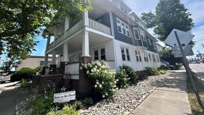 A two-story house with a porch, a brick foundation, and a sign advertising yoga classes.
