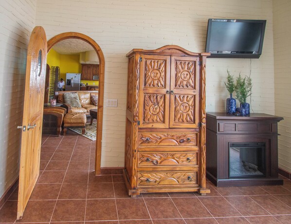 A wooden cabinet with intricate carvings, a television mounted on the wall, and a fireplace. - Ocean Front Baja Vacation (Playas de Rosarito)
