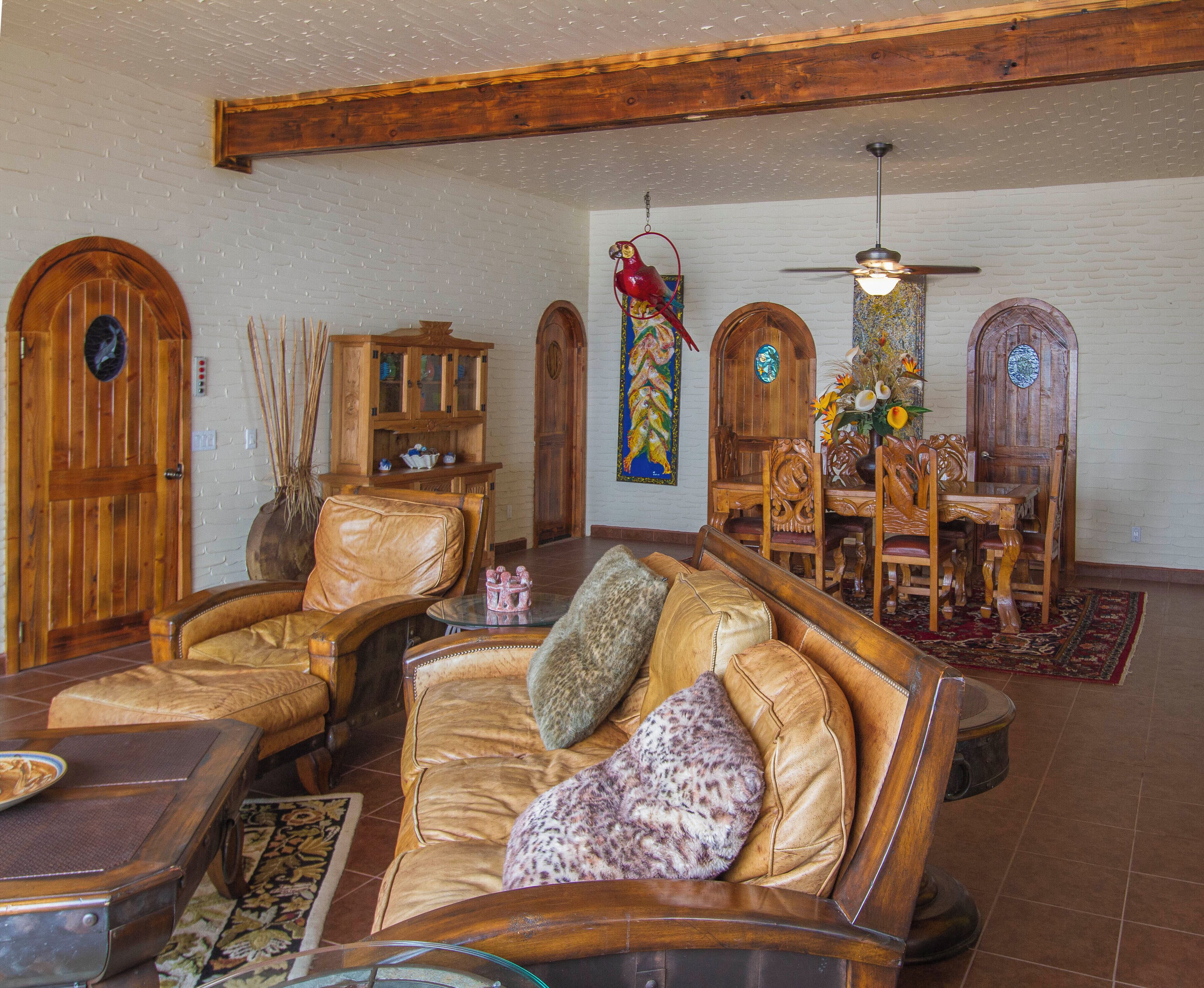 A spacious living room with leather furniture, wooden decor, and a dining area with a chandelier.