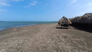 Ein Strand mit Lehmhütten und blauem Himmel.