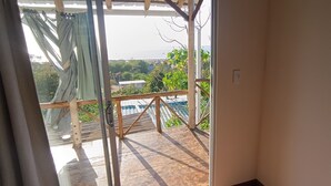 Ein Zimmer mit einer Schiebetür und Zugang zu einem Außenbereich mit Meer- und Grünblick.