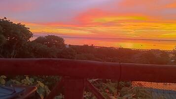 Vista do pôr do sol, com um corrimão vermelho em primeiro plano.