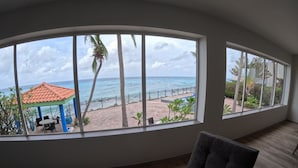 A room with large windows offering a view of the beach and ocean. - Welcome to the Dutch side of St. Maarten. 3 bedroom unforgettable ocean view. (Koolbaai)