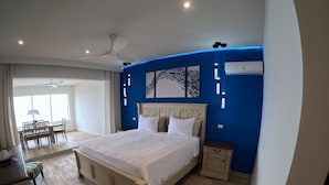 A bedroom with a large bed, a dining area with a table and chairs, and a view of the outdoors through a large window. - Welcome to the Dutch side of St. Maarten. 3 bedroom unforgettable ocean view. (Koolbaai)