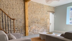 A living room with a stone wall, a wooden staircase, and a view of the outdoors. - Exceptional group gîte for families, friends, professionals 24 pers. (Lingèvres)