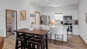 A modern kitchen with white cabinets, stainless steel appliances, and a wooden dining table with four chairs. - 
Fire Pit, Lake Views, Blackstone + Private Dock (Mabank)