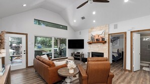 A spacious living room with a brown leather sofa, a round coffee table, and a fireplace. - 
Fire Pit, Lake Views, Blackstone + Private Dock (Mabank)