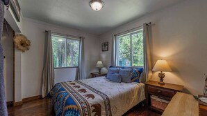 A bedroom with a bed, two bedside tables, a window, and a door.