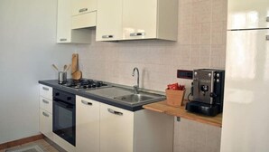 A modern kitchen with white cabinets, a stainless steel sink, a built-in oven, and a coffee machine. - The house on Via Argine, the flavors and colors of the countryside (Veneto)