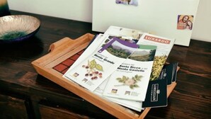 A wooden tray with brochures and a black card on a table. - The house on Via Argine, the flavors and colors of the countryside (Veneto)