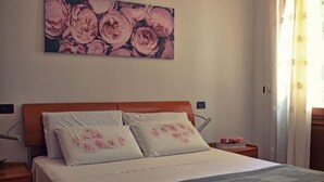 A bedroom with a wooden headboard, two pillows with floral designs, a bedspread, and a nightstand with a lamp. - The house on Via Argine, the flavors and colors of the countryside (Veneto)
