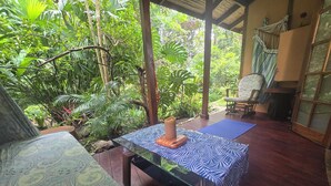Una habitación con una mesa de madera, un sofá estampado y una colchoneta de yoga azul.