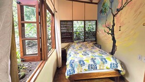 Un dormitorio con cama, ventana y un mural en la pared.