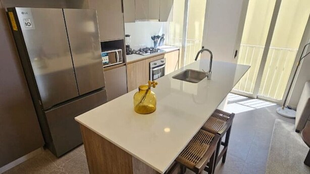 A modern kitchen with a central island, stainless steel appliances, and a view to a balcony. - Incredible new apartment in Centro Zapopan 304A (Zapopan)