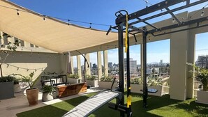 A rooftop gym with exercise equipment, a bench, and a view of the city skyline. - Incredible new apartment in Centro Zapopan 304A (Zapopan)