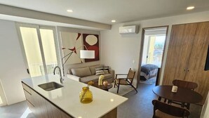 A modern kitchen with a central island, a dining area with a round table, and a living space with a sofa and chairs. - Incredible new apartment in Centro Zapopan 304A (Zapopan)