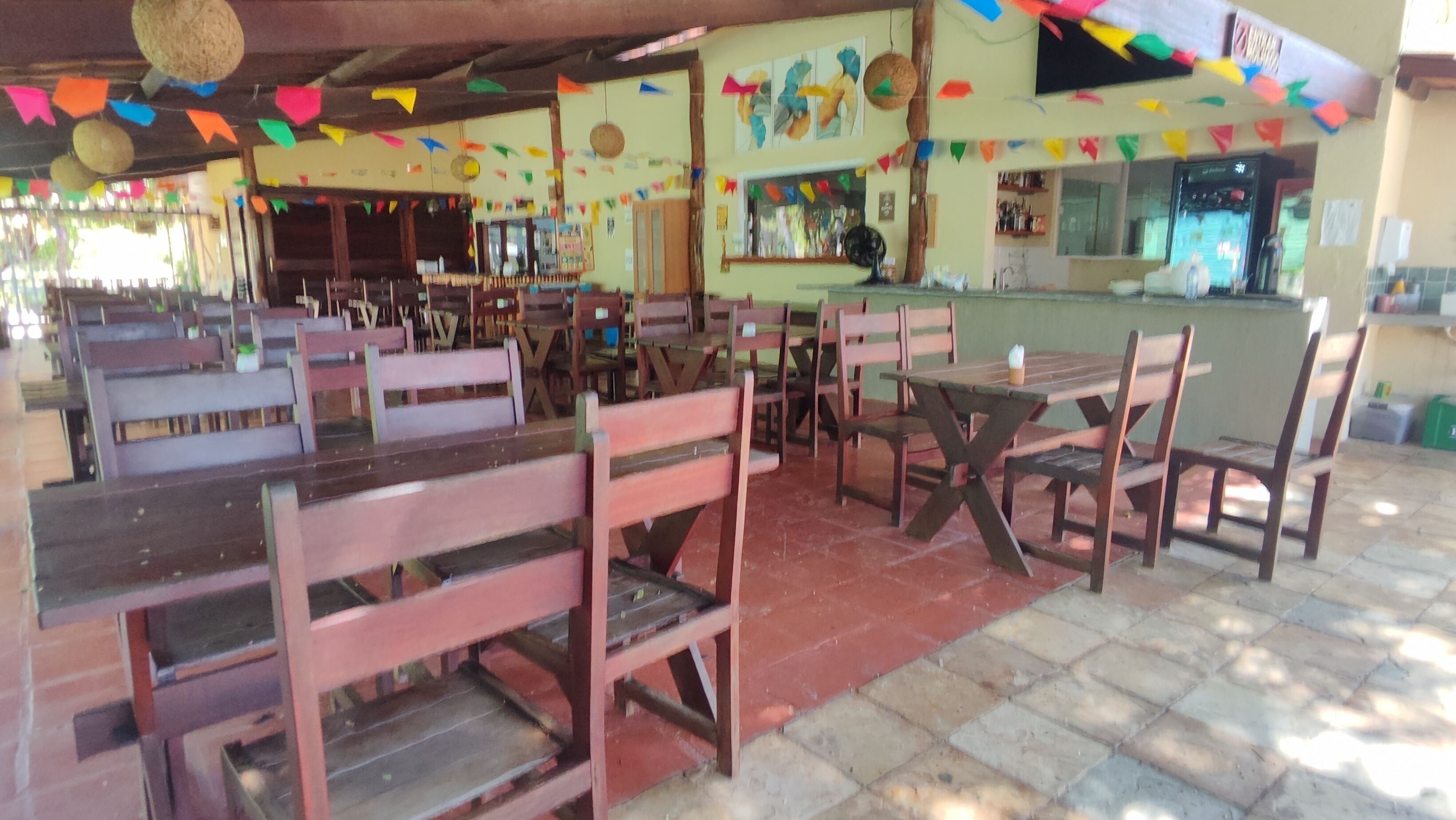 A restaurant with wooden tables and chairs, colorful decorations, and a counter area.