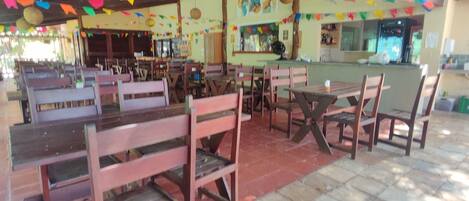 A restaurant with wooden tables and chairs, colorful decorations, and a counter area.