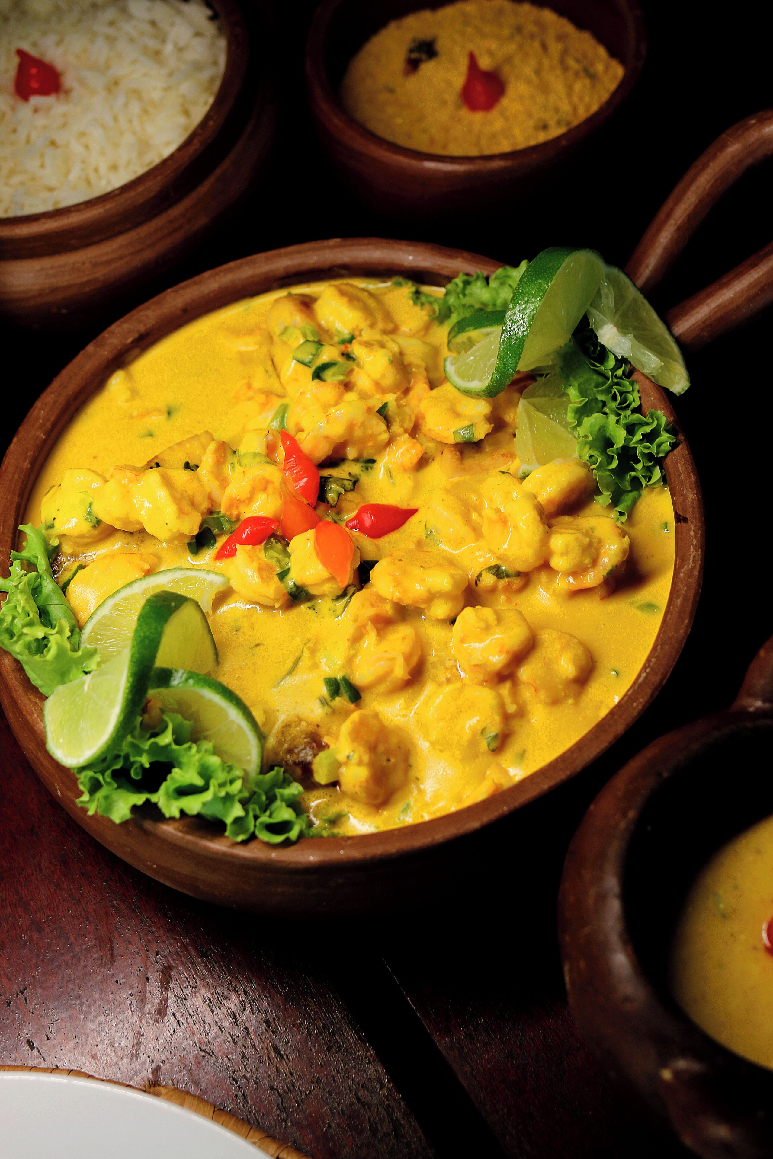 A bowl of curry with lime and lettuce garnish.