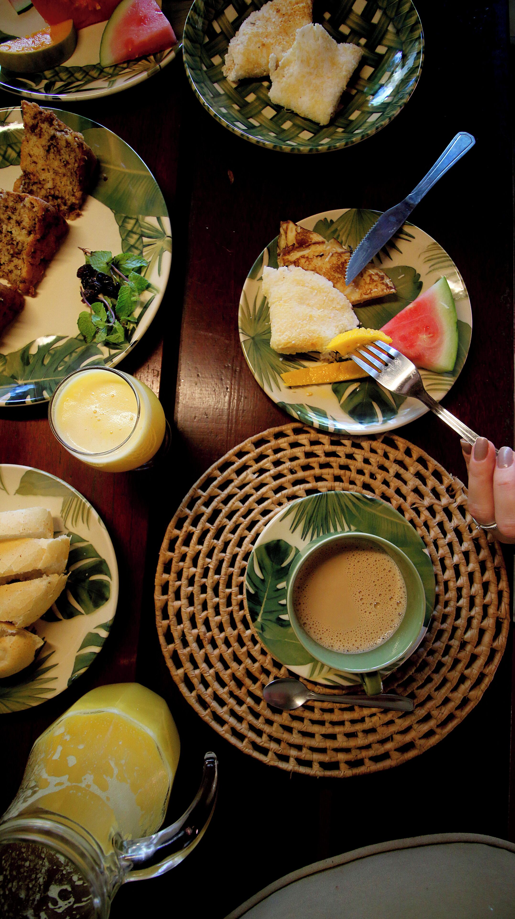 Une table dressée avec divers éléments pour le petit-déjeuner, notamment des toasts, des fruits et une tasse de café.