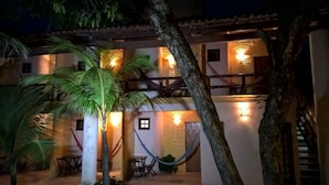 A two-story building with a balcony, a hammock, and a palm tree.