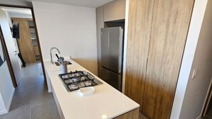 A modern kitchen with a central island, stainless steel appliances, and a wooden cabinet. - Incredible new apartment in Centro Zapopan 603A (Zapopan)