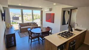 A modern kitchen with a central island, dining area with chairs, and a large window offering a city view. - Incredible new apartment in Centro Zapopan 603A (Zapopan)