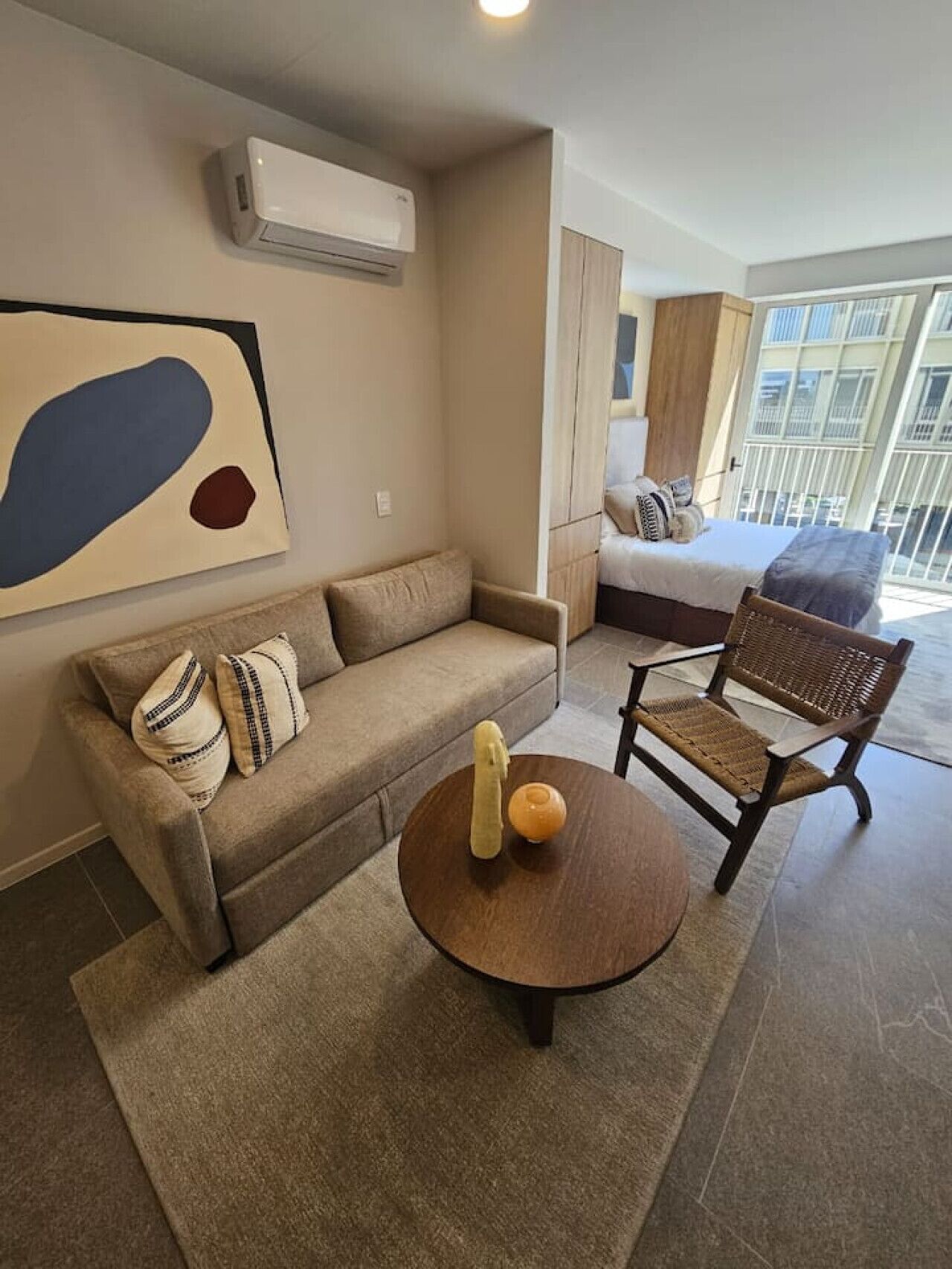 A modern living room with a sofa, a wooden coffee table, and a wicker chair.