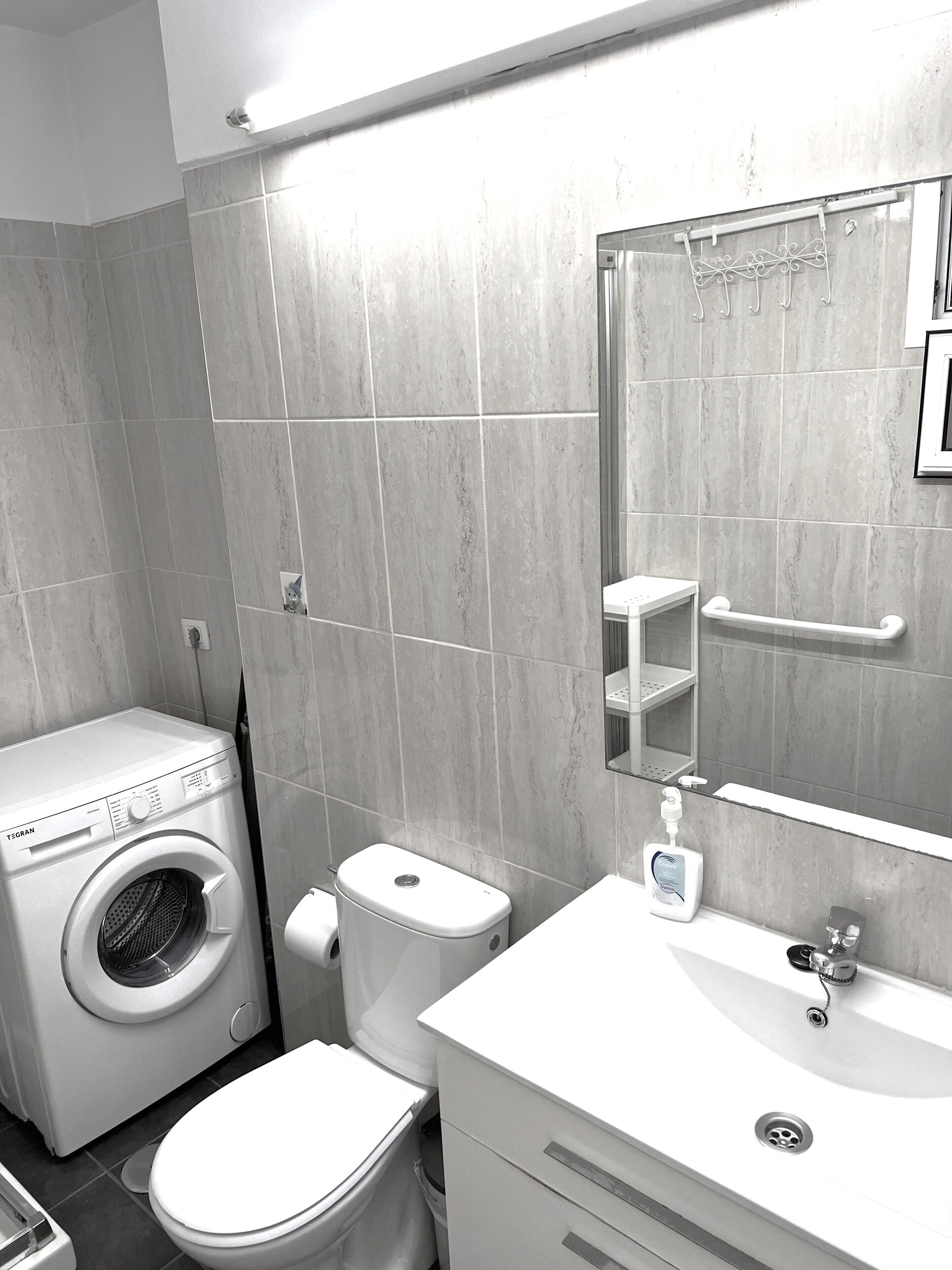 Een kleine badkamer met een wasmachine, toilet en wastafel.