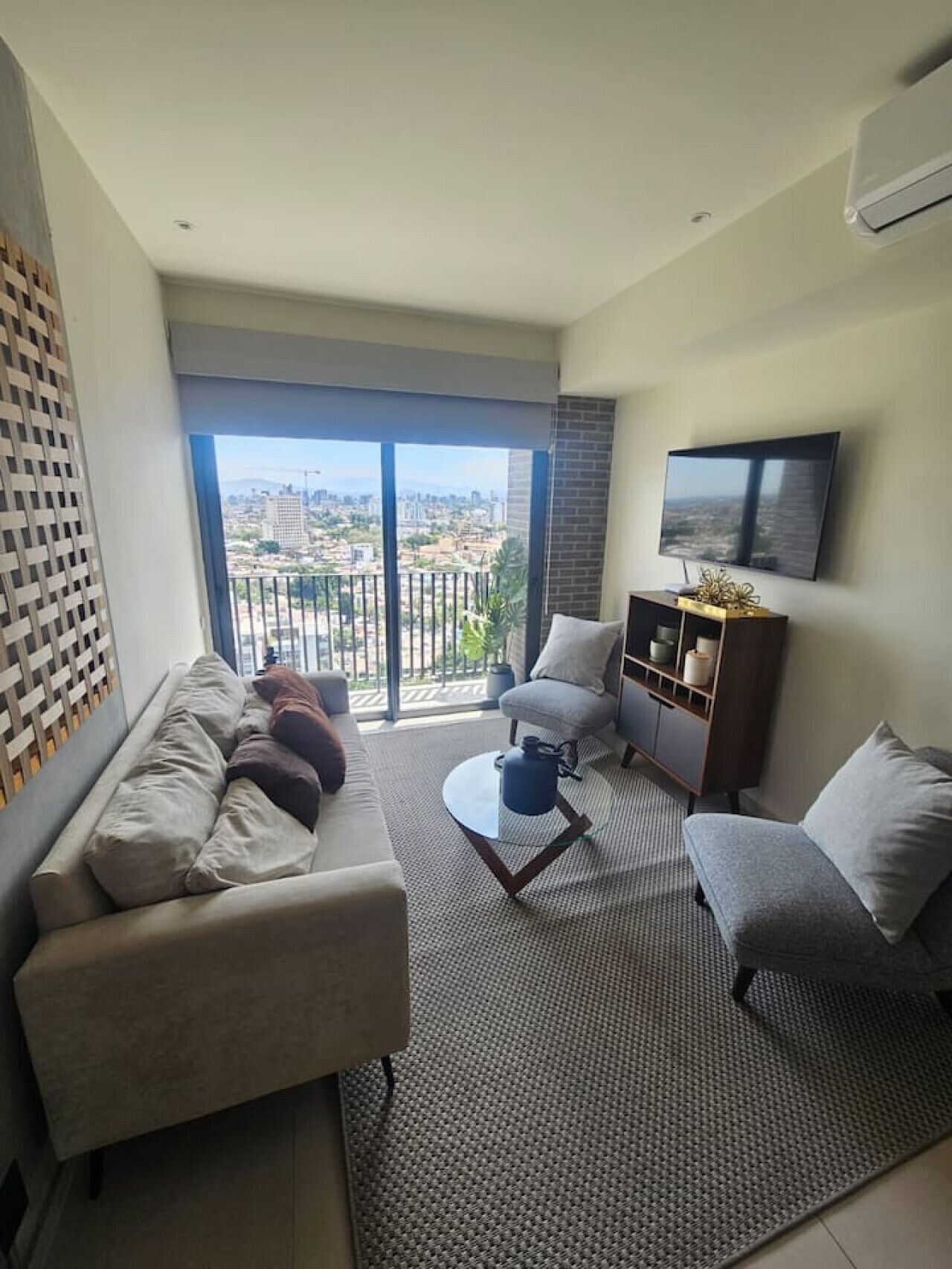 Una sala de estar moderna con un sofá, sillones, una mesa de centro y un televisor.