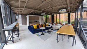 An open-plan space with a long table, a sofa with colorful cushions, and a coffee table.