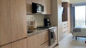 A modern kitchen with wooden cabinets, a microwave, stove, and a coffee maker.