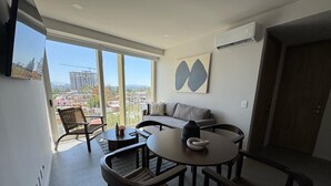 A modern living room with a round table, two sofas, and wicker chairs.