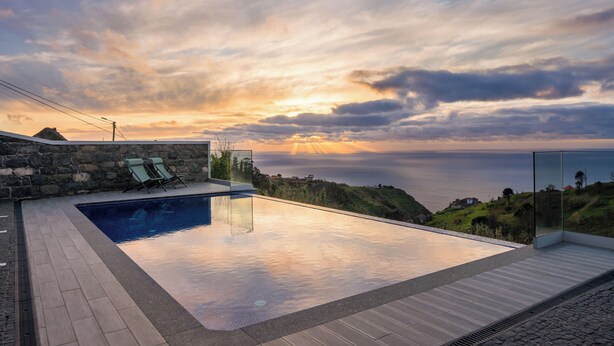 Ein moderner Infinity-Pool mit freiem Blick auf das Meer und einen Sonnenuntergang.
