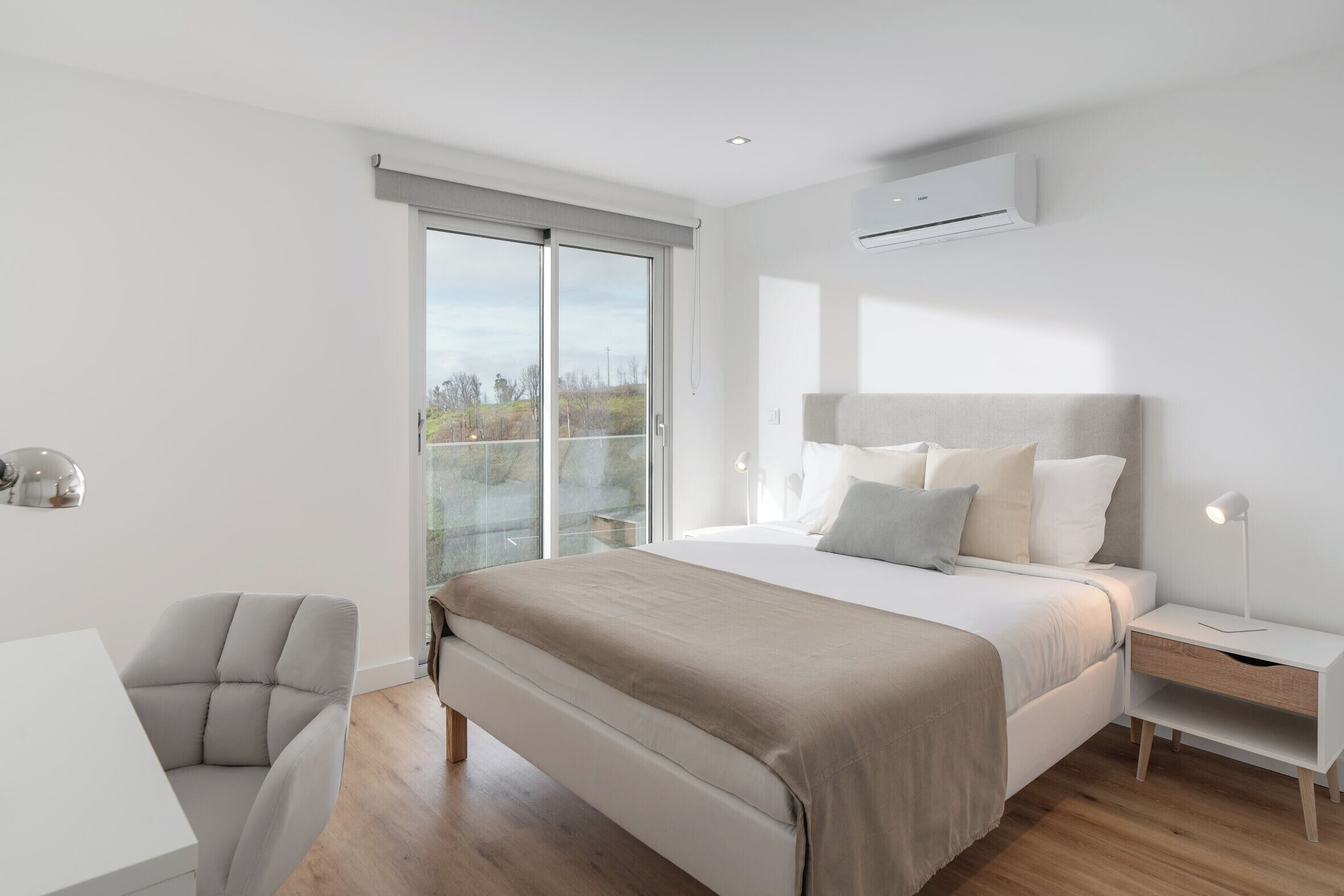 A modern bedroom with a large bed, a desk, and a chair.