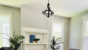 A living room with a fireplace, a black leather chair, a white coffee table, a grey sofa, and a patterned rug. - Historic Garden 1-bedroom apartment in amazing Augusta - The Pearl with AC, WiFi (Augusta)