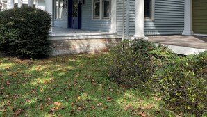 A two-story house with a covered porch, a blue door, and a brick foundation. - Historic Garden 1-bedroom apartment in amazing Augusta - The Pearl with AC, WiFi (Augusta)