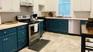 A kitchen with teal cabinets, a stainless steel stove, and a window with blinds. - Historic Garden 1-bedroom apartment in amazing Augusta - The Pearl with AC, WiFi (Augusta)