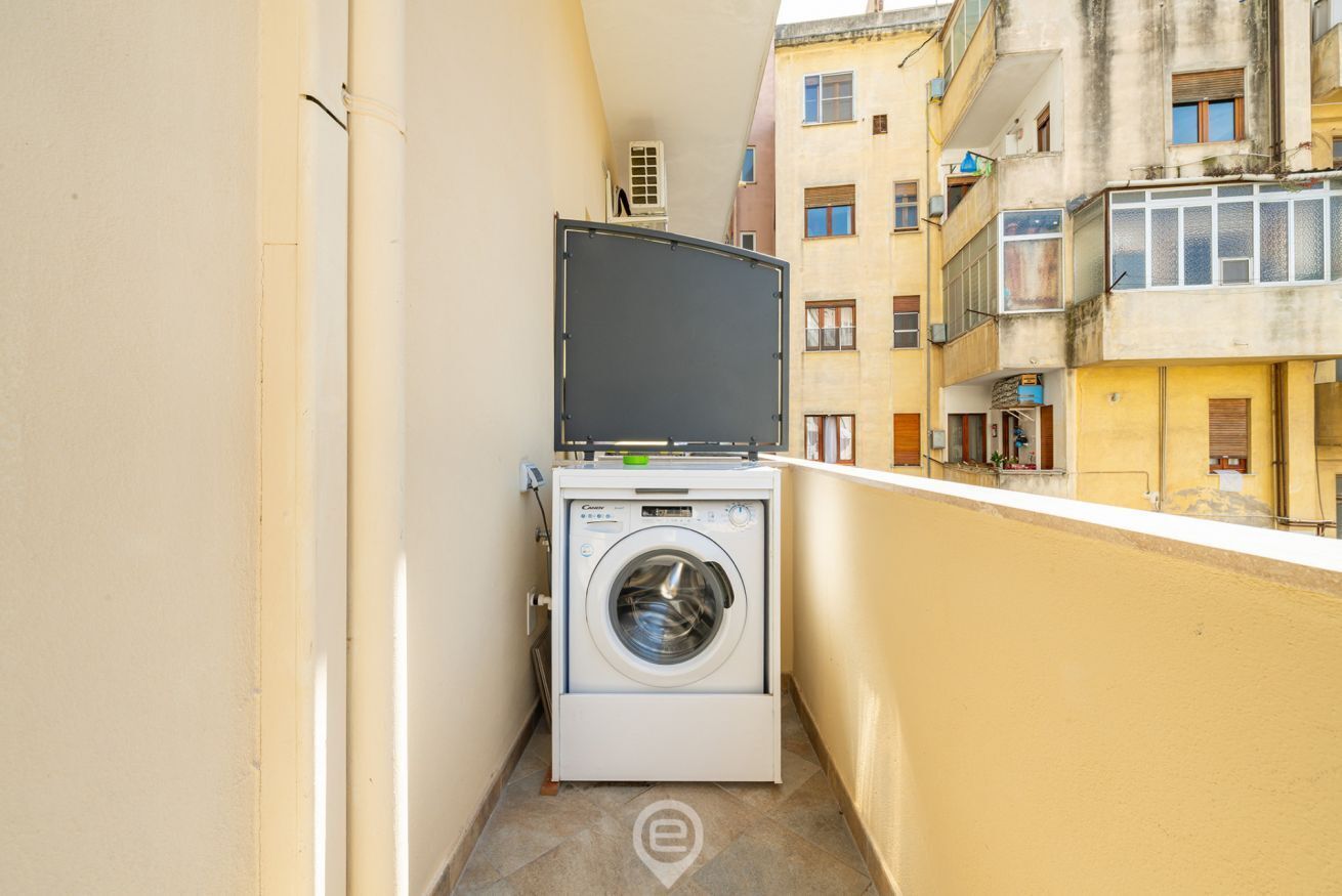 Un petit balcon avec un lave-linge et un grand écran.