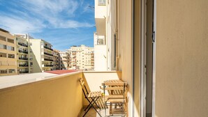 Varanda com mesa e cadeiras, vista para área residencial com vários edifícios.